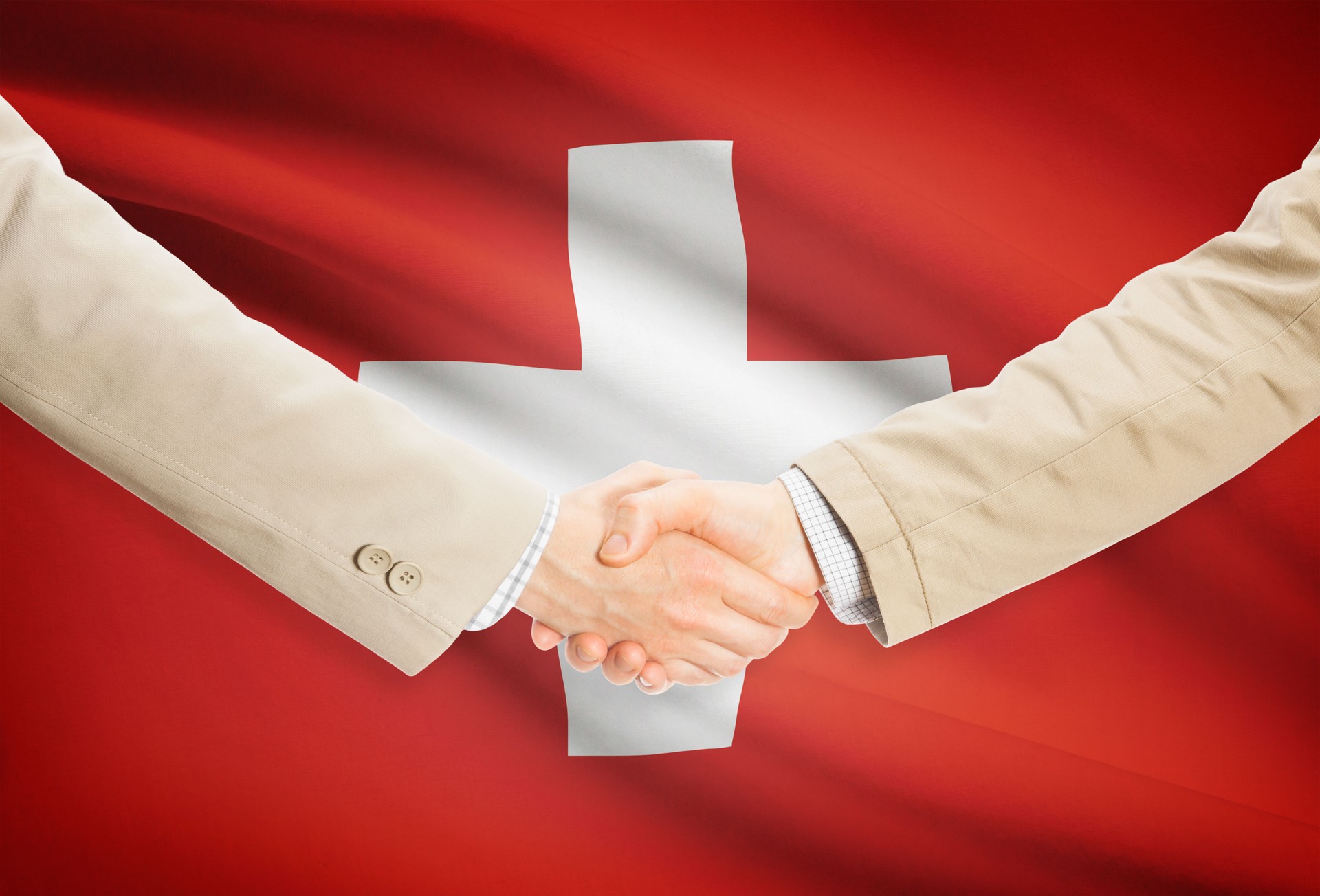 Unternehmer-Handshake mit Fahne im Hintergrund - Schweiz